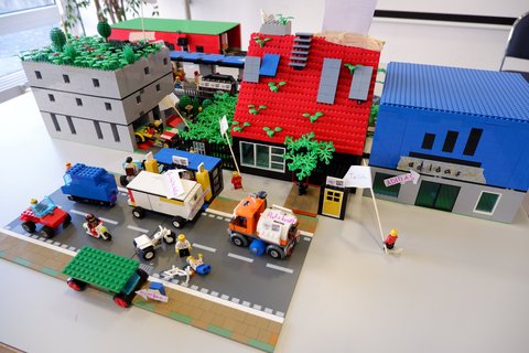 Lego-Modell des Teams "Schlafkoje" mit Straße, Bushaltestelle, Parkhaus und Kiosk mit Schlafkojen unter dem Dach.